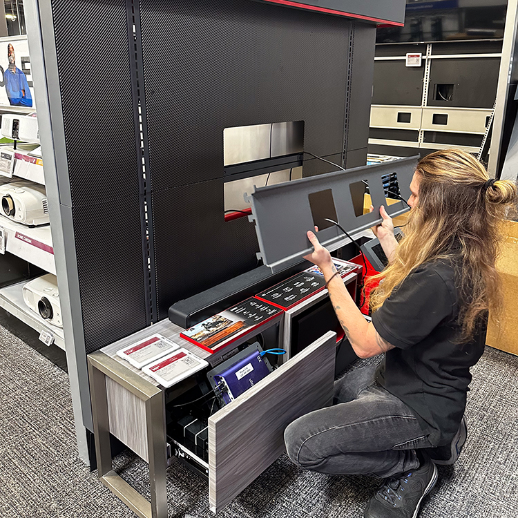 a merchandising professional is installing a tv mount on a display