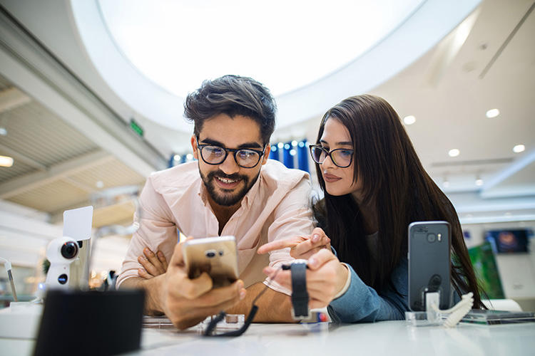 a woman helps a man choose a new smartphone in a retail store