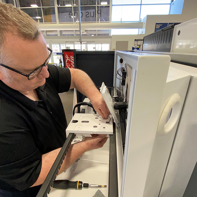 a male technician works on a display at an electronics store
