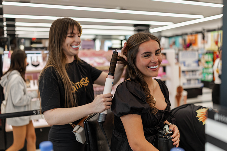 A brand advocate demonstrates a hair styling tool on a customer.