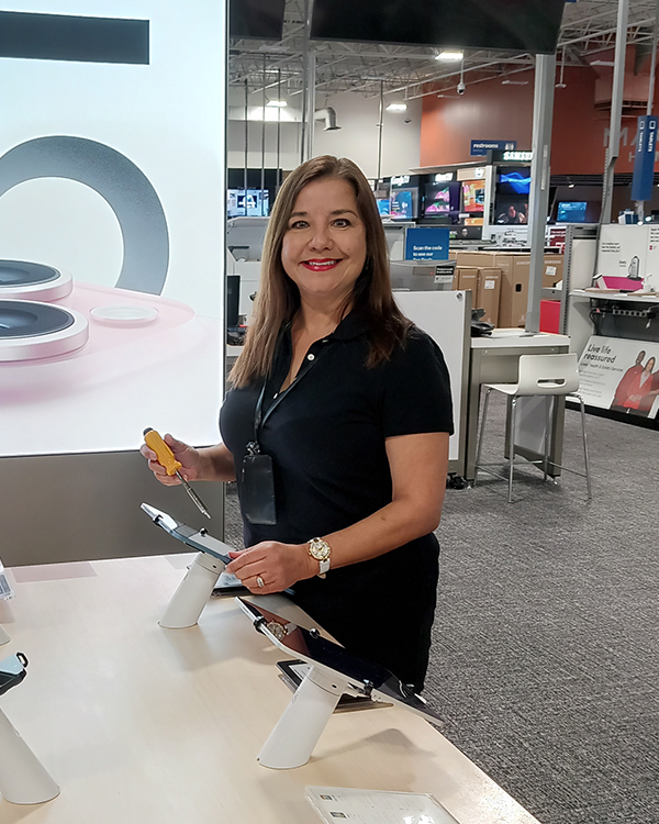 A woman smiles as she finishes installing a tablet on a merchandise display